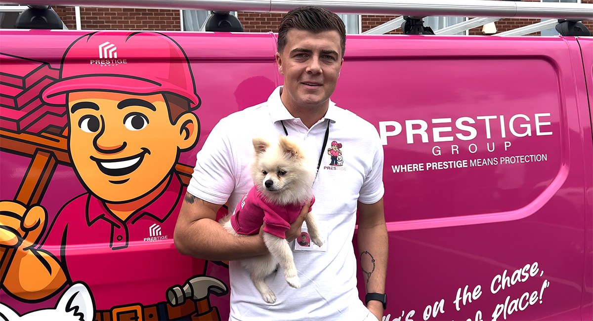 Luke from Prestige Pave & Resin holding Bella in front of the bright pink company van